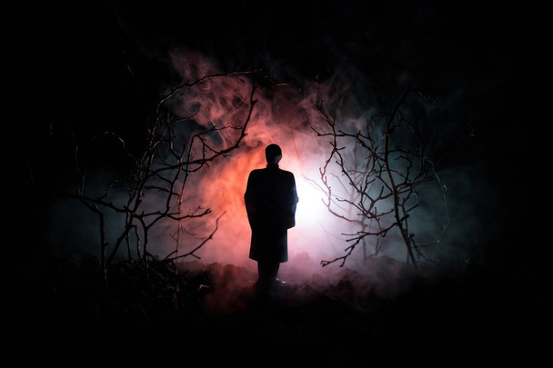 étrange silhouette dans une sombre forêt effrayante la nuit, paysage mystique lumières surréalistes avec homme effrayant. tonique
 - Photo, image