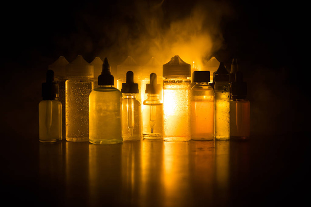 Vape concept. Smoke clouds and vape liquid bottles on dark background. Light effects - Photo, Image
