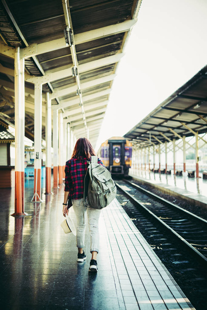 Giovane hipster donna in attesa sulla piattaforma della stazione con zaino. Concetto di viaggio
. - Foto, immagini