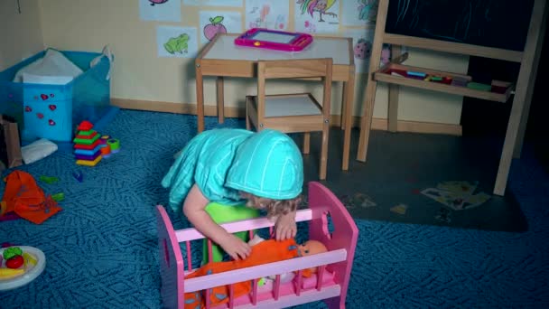 νήπιο παιδί καθορίζουν παιχνίδι κούκλα μωρό και ταλαντεύεται στο παχνί κρεβάτι. - Πλάνα, βίντεο