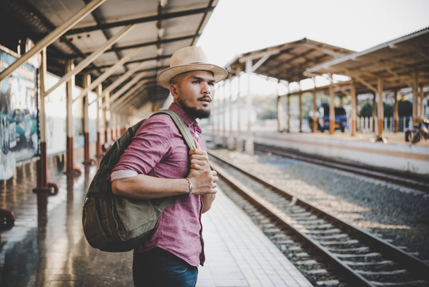 流行に敏感な若い男は駅を歩きます。プラットフォームで電車を待っている人。旅行の概念. - 写真・画像
