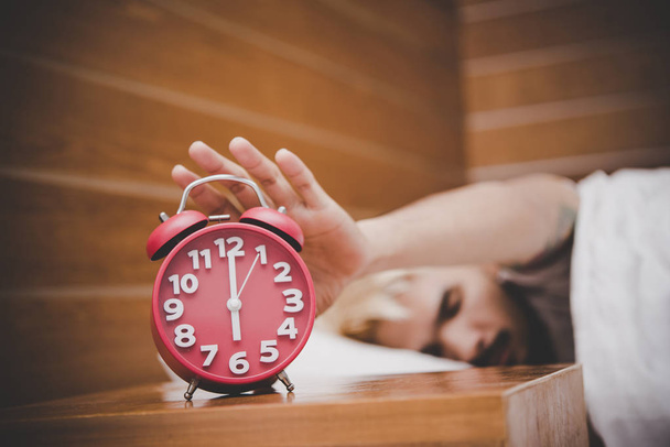 Man trying to turn off the alarm clock waking up at morning. - Foto, Imagem