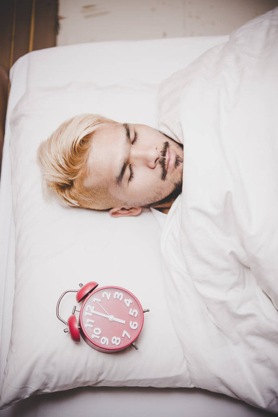 sleepy man with alarm clock waking up at morning. - Photo, Image