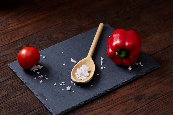Vegetarian still life with fresh grape tomatoes, pepper and salt in wooden spoon on wooden background, selective focus - Foto, Bild