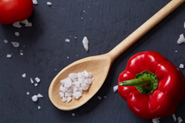 Vegetarian still life with fresh grape tomatoes, pepper and salt in wooden spoon on wooden background, selective focus - Foto, afbeelding