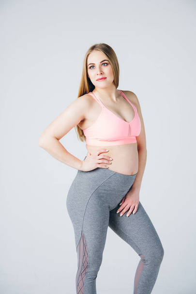 Pregnant girl in sportswear is engaged in fitness - Fotoğraf, Görsel