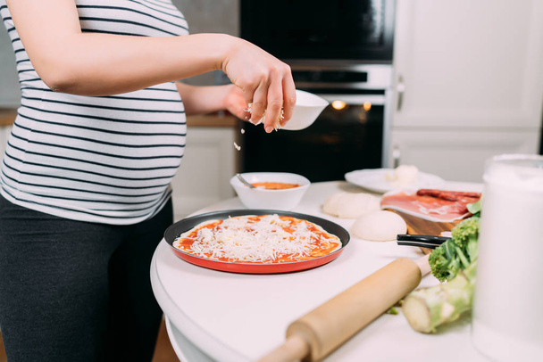 dettagli ravvicinati della donna incinta che fa la pizza a casa
 - Foto, immagini