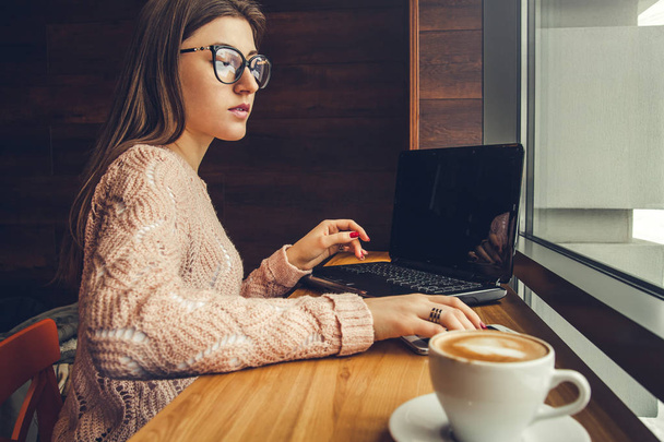 Genç kadın serbest meslek sahibi bir çağrı bir dizüstü bilgisayar kullanarak kafede alır. - Fotoğraf, Görsel