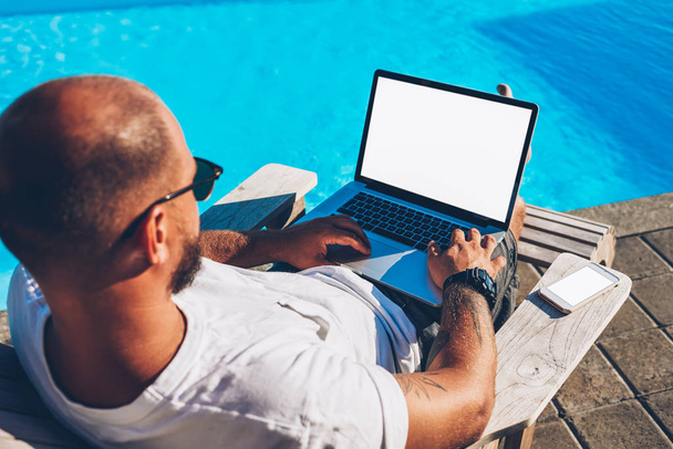 Top view of male freelancer searching information on internet websites and working at modern netbook with blank copy space screen for your advertising information content while lying on sunbed - Photo, Image