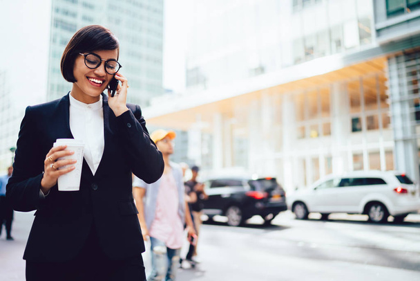 Cheerful businesswoman in elegant wear talking on cellular while standing outdoors near copy space area for financial news.Successful female director of company calling on telephone - Φωτογραφία, εικόνα