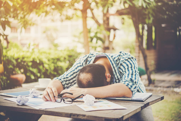 Втомлений робочий чоловік спить на робочому місці, повний роботи
. - Фото, зображення