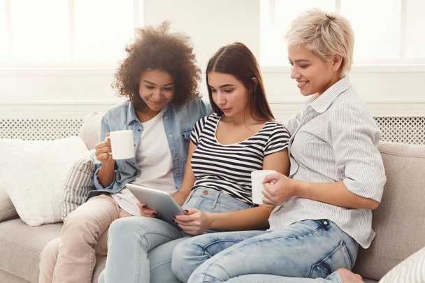 Три щасливі друзі-жінки використовують планшет і п'ють каву
 - Фото, зображення
