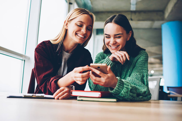 Happy best friends laughing during watching funny videos on internet websites enjoying social media life during break.Two cheerful female bloggers reading positive comments on smartphone device - Foto, Bild