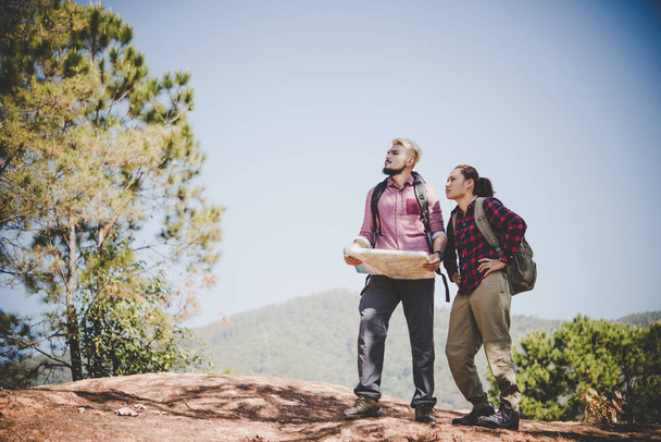 junges Touristenpaar, das im Urlaub in den Bergen auf der Suche nach Sehenswürdigkeiten die Landkarte betrachtet. Reisekonzept. - Foto, Bild