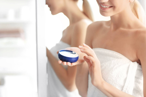 Young woman with jar of body cream at home - Foto, Imagen