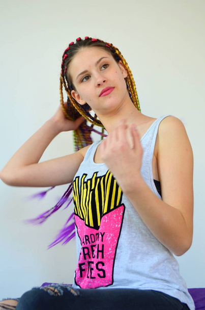 ein Mädchen mit einem modischen Satz von bunten Zöpfen kanekalon. gefärbte künstliche Haarsträhnen. Material zum Flechten von Zöpfen. - Foto, Bild