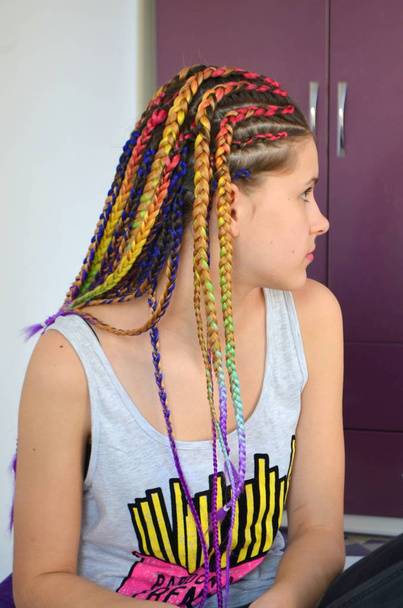 Una chica con un conjunto de moda de trenzas multicolores Kanekalon. Hilos artificiales coloreados de cabello. Material para trenzas trenzables
. - Foto, Imagen