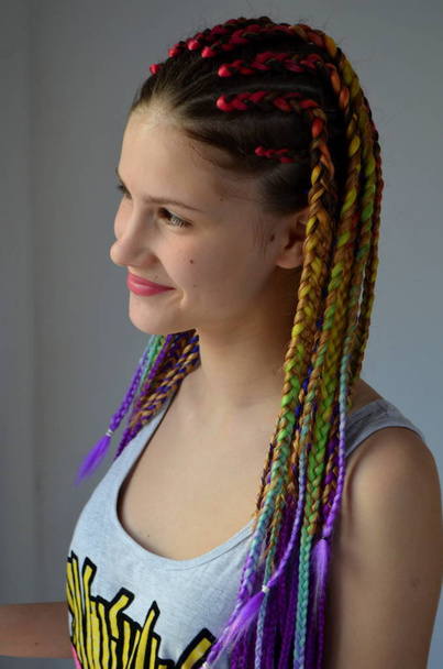 Una chica con un conjunto de moda de trenzas multicolores Kanekalon. Hilos artificiales coloreados de cabello. Material para trenzas trenzables
. - Foto, imagen