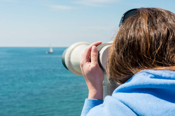 Woman looking through coin operated binoculars at seaside. - Foto, immagini