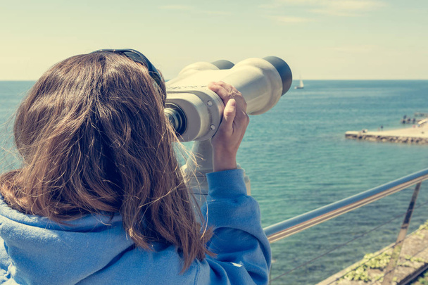 Woman looking through coin operated binoculars at seaside. - Foto, immagini