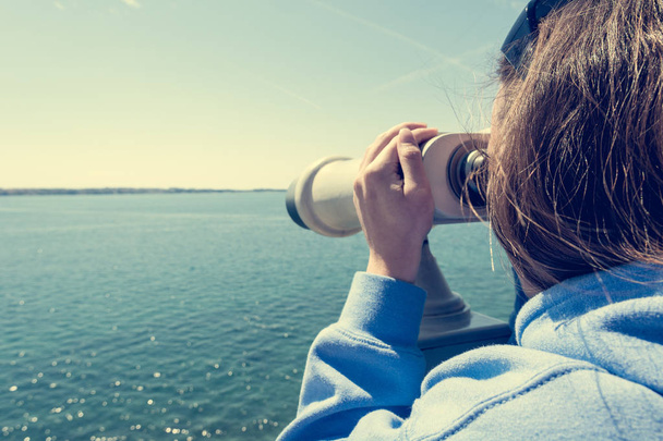 Žena, která se dívá přes mince ovládané dalekohledem na pobřeží. - Fotografie, Obrázek