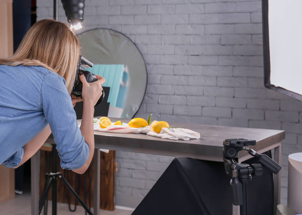 Woman taking photo of food with professional camera in studio - Fotó, kép