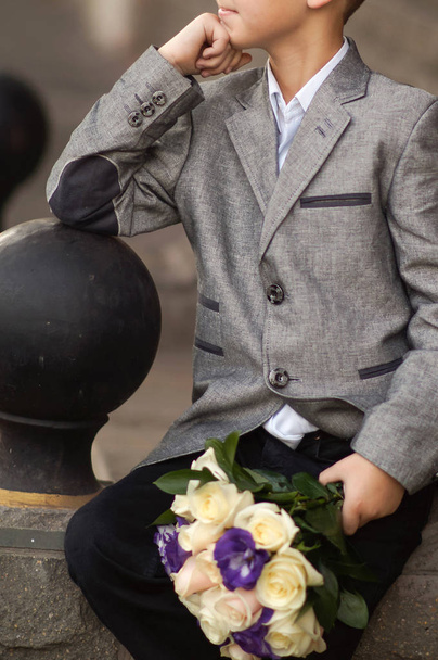 the boy is holding a bouquet of flowers - Foto, Imagem