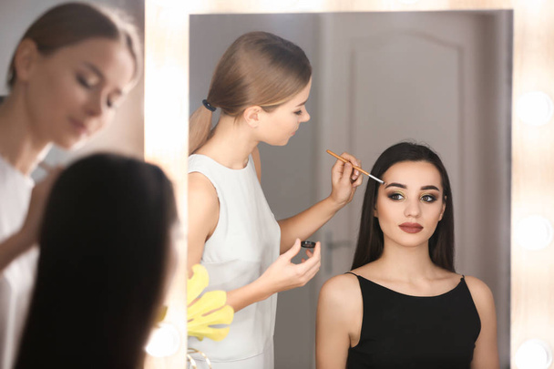 Professional visage artist applying makeup on woman's face in salon - Zdjęcie, obraz