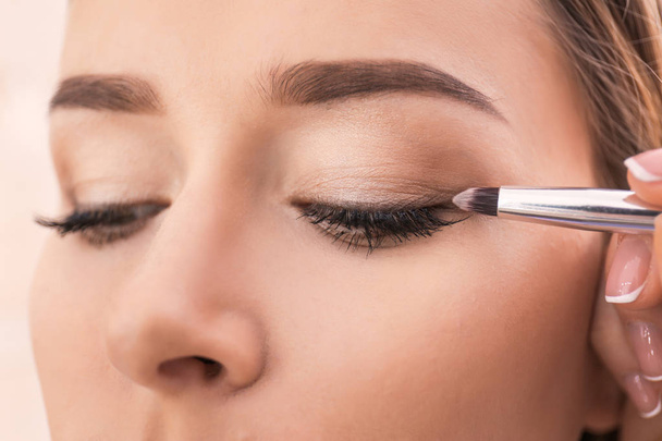 Professional visage artist applying makeup on woman's face in salon, closeup - Фото, изображение