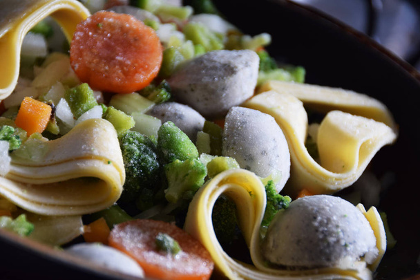 frozen tagliatelle pasta with vegetables in a pan - 写真・画像