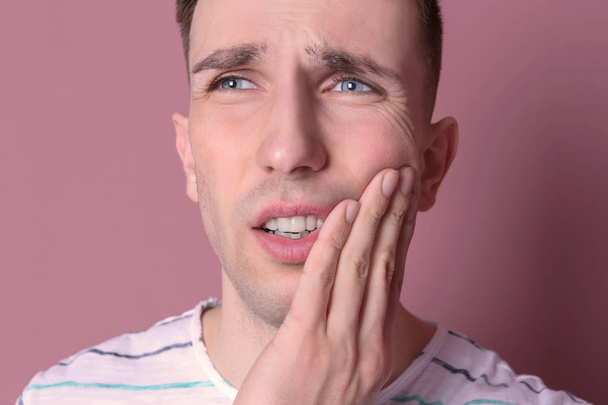 Young man with sensitive teeth on color background, closeup - Foto, afbeelding