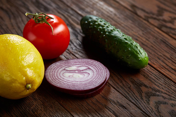 Still life of fresh organic vegetables on wooden plate over wooden background, selective focus, close-up - Φωτογραφία, εικόνα