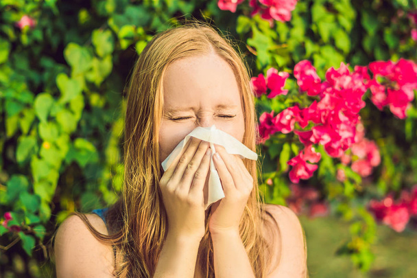 Pollen allergy concept. Young woman is going to sneeze. Flowering trees in background. - Foto, imagen
