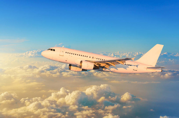 fliegendes Flugzeug über den Wolken Horizont Himmel mit hellen Farben Sonnenuntergang. - Foto, Bild