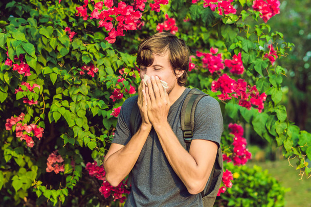 Young man sneezes because of an allergy to pollen. - Fotoğraf, Görsel