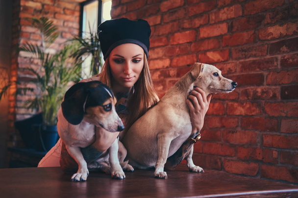 Una mujer rubia tatuada con estilo en camiseta y jeans con sus perros
 - Foto, imagen