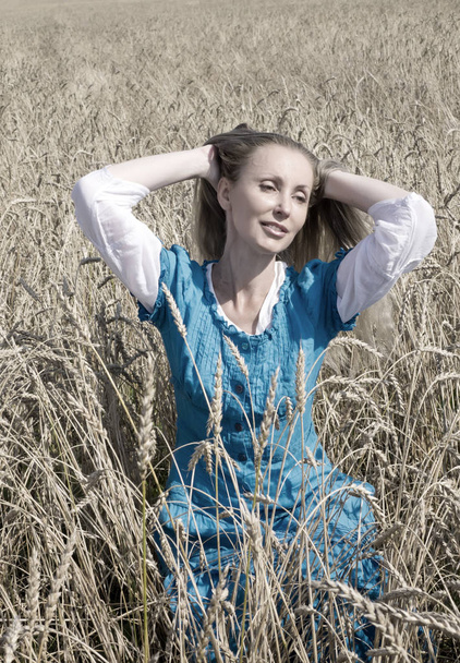 La hermosa mujer en un vestido largo azul en el campo de las espigas maduras de cereales, retro effec
 - Foto, imagen