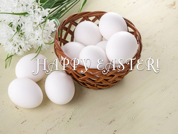 Easter background. Basket with eggs and a bouquet of the first color on a wooden background. With congratulatory text - Foto, immagini