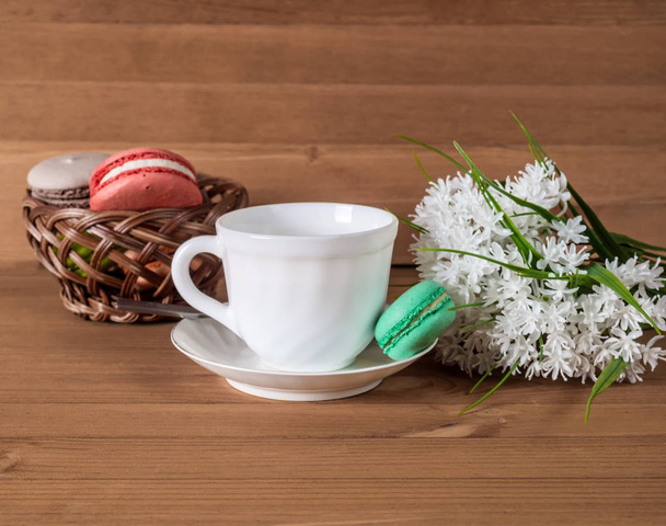 Colorful macarons with tea and flowers on wooden table. - Foto, immagini