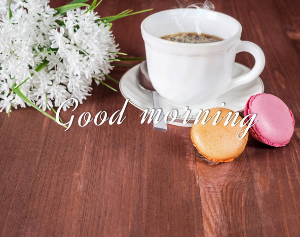 Cup of coffee, French macarons and a white bouquet of flowers on a wooden background - Fotoğraf, Görsel
