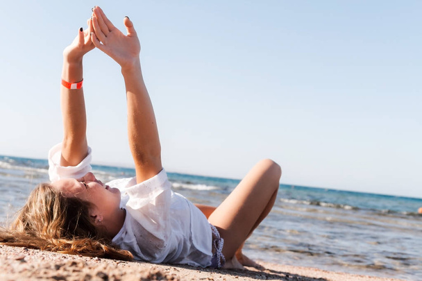 Młody dorosły opalona blond dziewczyna leży na piasku na plaży w pobliżu - Zdjęcie, obraz