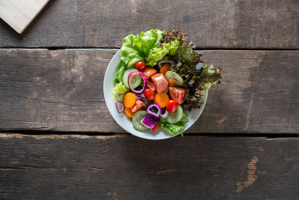 Верхний вид на свежий овощной салат на деревянном фоне
 - Фото, изображение