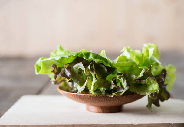 Fresh green lettuce salad in wooden dish.  - Фото, зображення