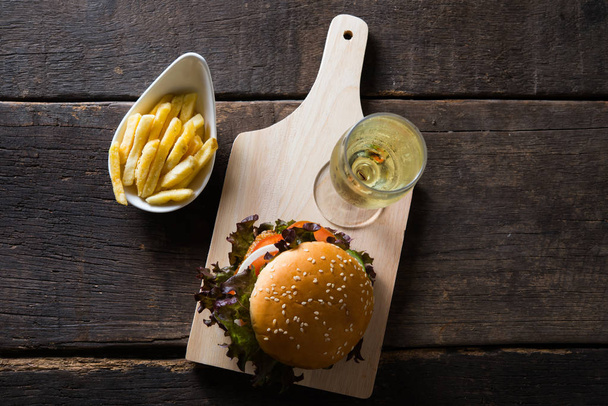 Top view of Home made chicken burger with champagne,french fries, lettuce, tomato and onion on wooden board. - Photo, Image