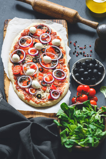 Homemade pizza with black olives, mozzarella cheese, purple onion and tomato sauce - Фото, изображение