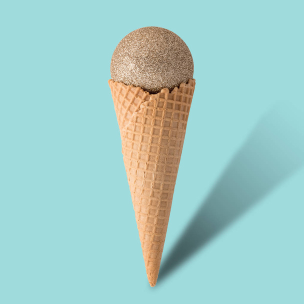 Ice cream cone with christmas ball on bright blue background. - Foto, afbeelding