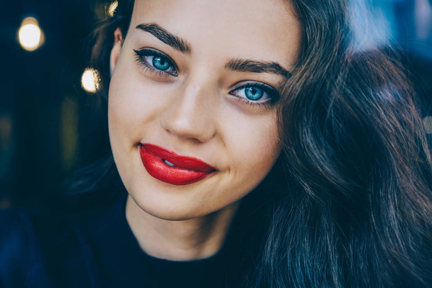 Cropped portrait of gorgeous brunette young woman with beautiful blue eyes and charming smile on face.Close up image of Ukrainian attractive female 20 years old with red lips looking at camera and smiling - Zdjęcie, obraz