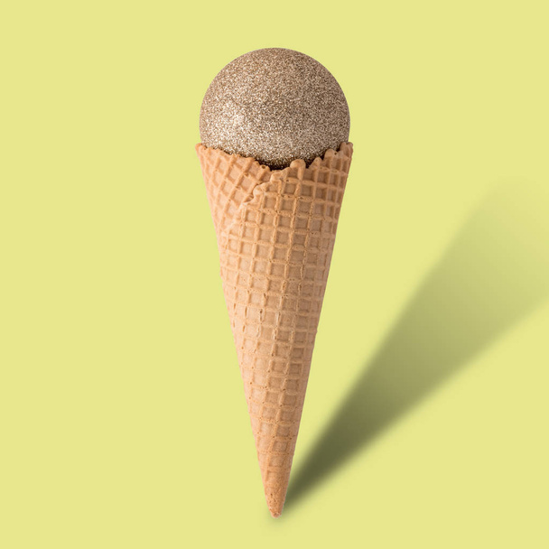 Ice cream cone with christmas ball on bright yellow background.  - Foto, afbeelding