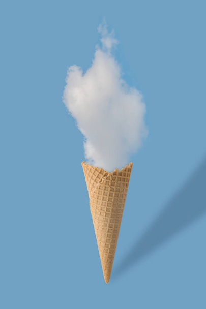 Ice cream cone and white cloud on pastel blue background.  - Фото, изображение