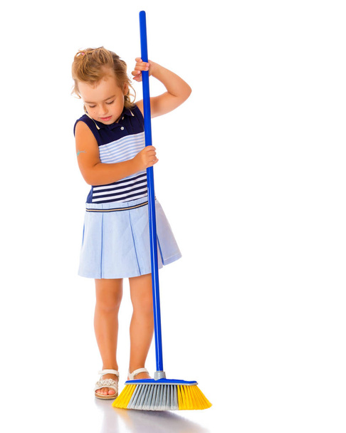 The little girl is sweeping the floor. - Foto, Imagen
